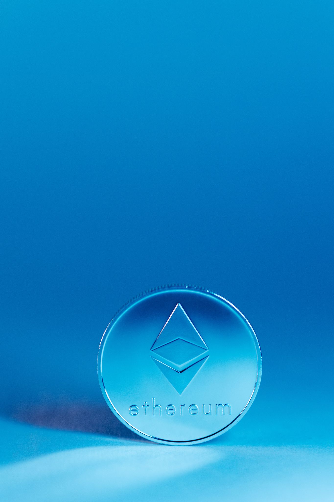 A close-up of an Ethereum coin against a vivid blue background, symbolizing cryptocurrency and digital finance.
