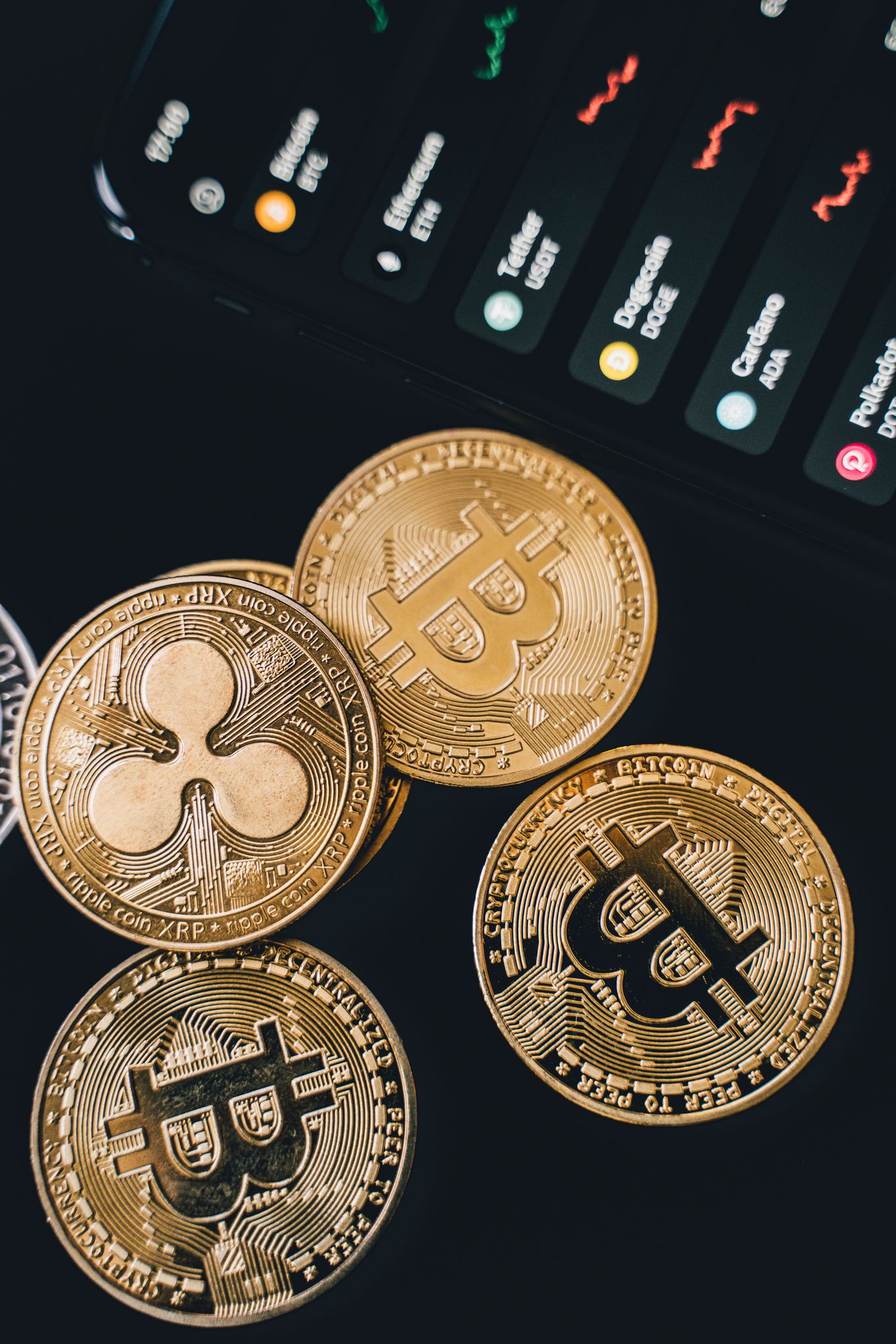 A detailed view of Bitcoin and Ripple coins with market data on a screen, symbolizing digital currency trends.